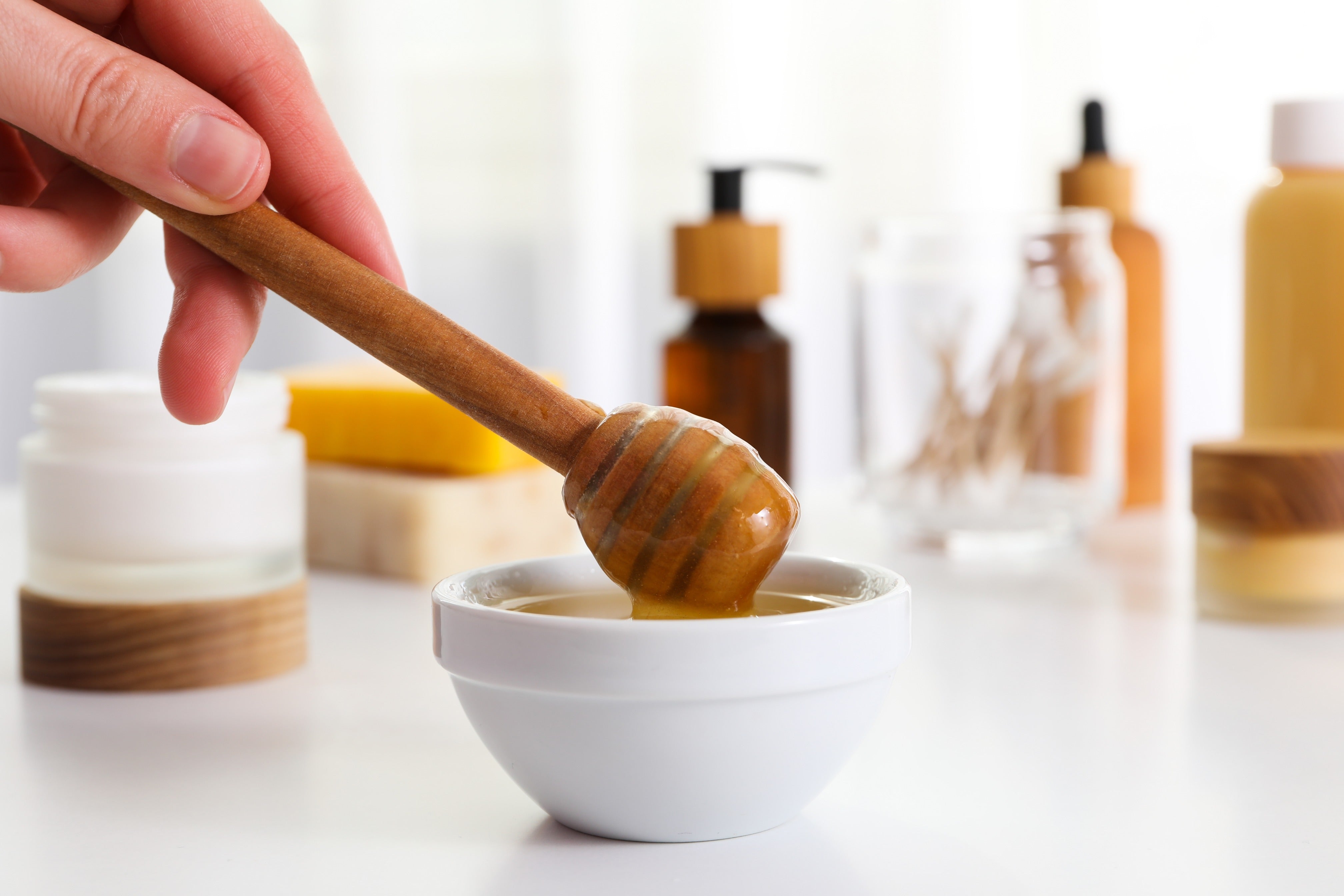 Raw honey dripping from a wooden dipper, used for skin care